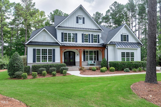 view of front of home with a shingled roof, board and batten siding, a front yard, a standing seam roof, and covered porch