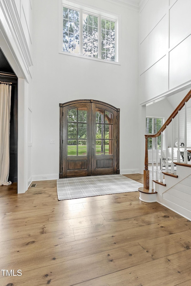 foyer featuring a high ceiling, wood-type flooring, french doors, baseboards, and stairway