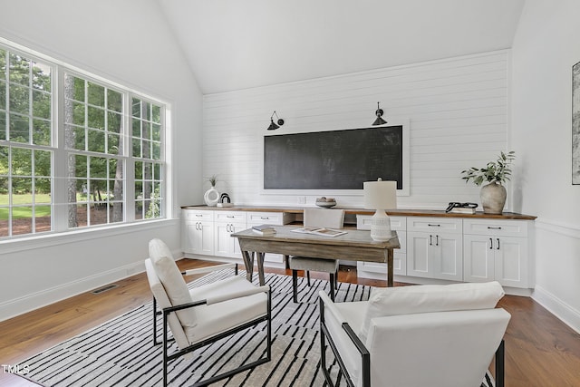 interior space with baseboards, lofted ceiling, wood finished floors, and visible vents