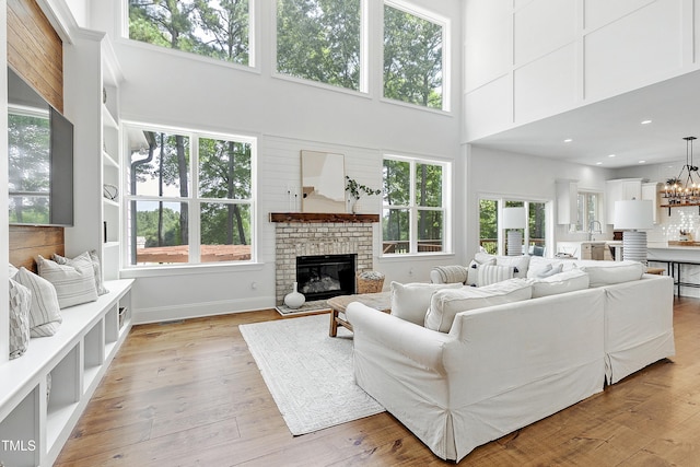 living area featuring a brick fireplace, a wealth of natural light, and a towering ceiling