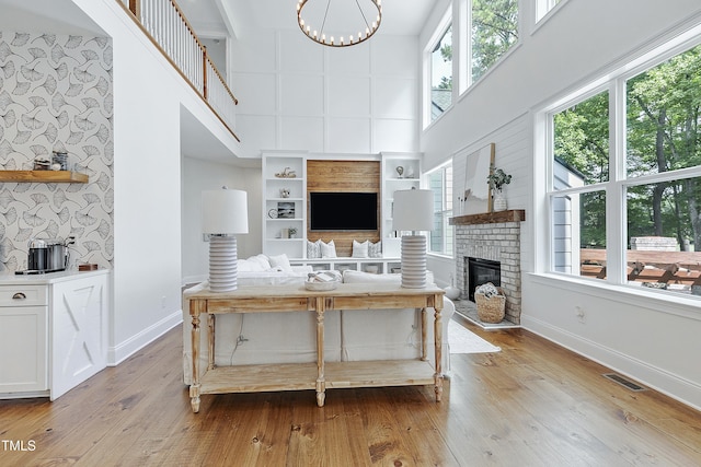 living area with baseboards, a high ceiling, a fireplace, and light wood finished floors