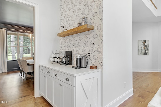 bar with backsplash, baseboards, and light wood-style floors