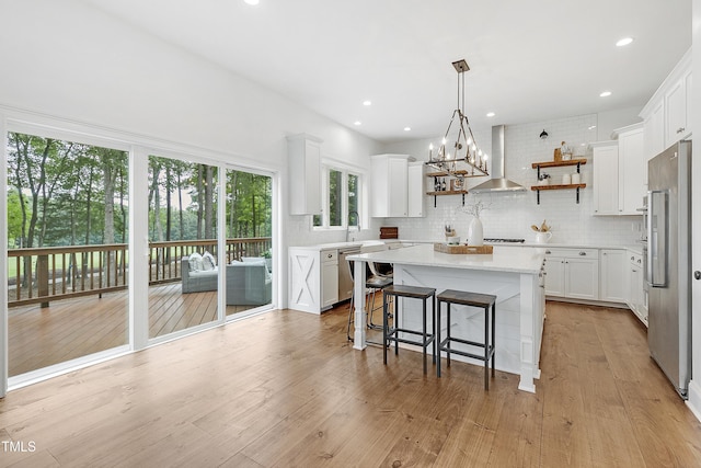 kitchen with appliances with stainless steel finishes, decorative backsplash, open shelves, and wall chimney exhaust hood