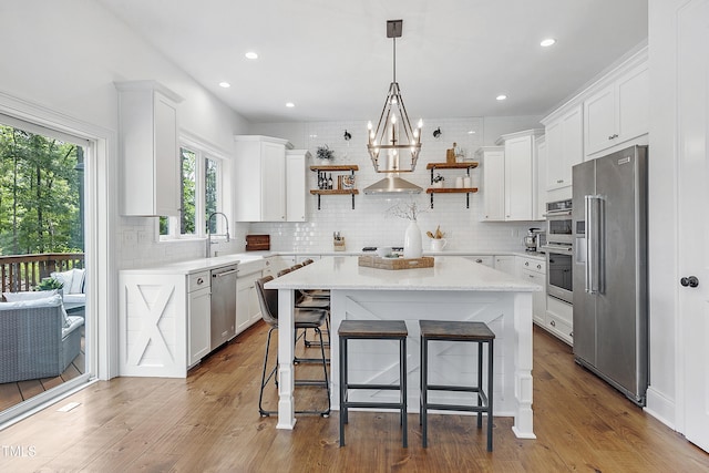 kitchen featuring open shelves, a sink, stainless steel appliances, tasteful backsplash, and a kitchen island