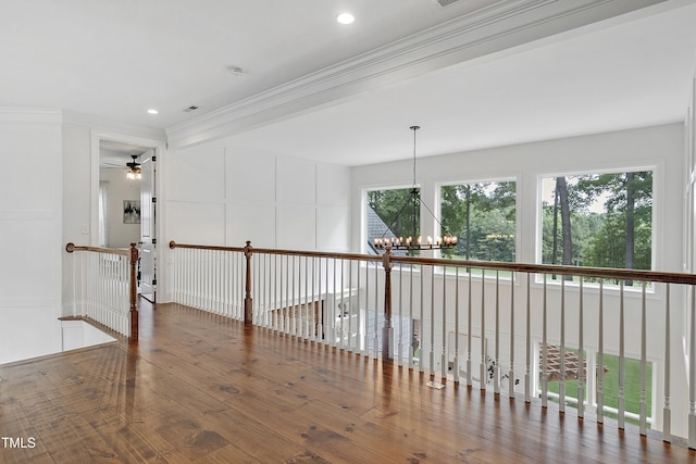 corridor featuring a healthy amount of sunlight, crown molding, wood finished floors, and a chandelier