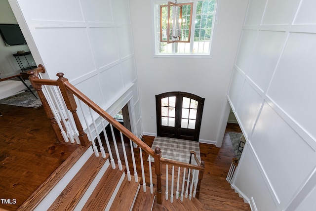 foyer entrance with stairway, a decorative wall, french doors, and dark wood finished floors