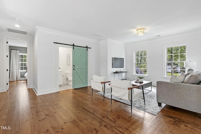 living room with crown molding, a barn door, and visible vents