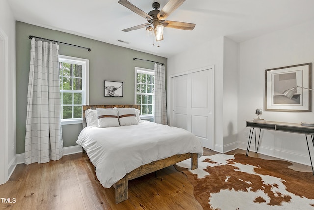 bedroom with baseboards, visible vents, multiple windows, and a closet