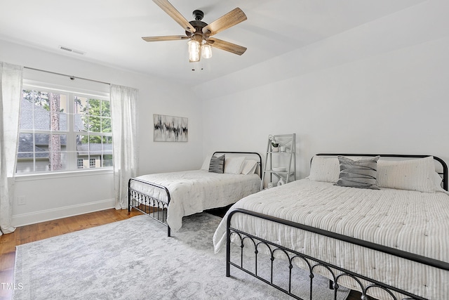 bedroom featuring visible vents, a ceiling fan, baseboards, and wood finished floors