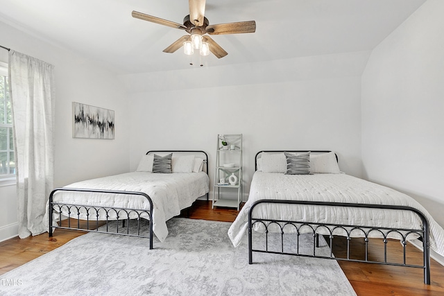 bedroom with ceiling fan, baseboards, vaulted ceiling, and wood finished floors