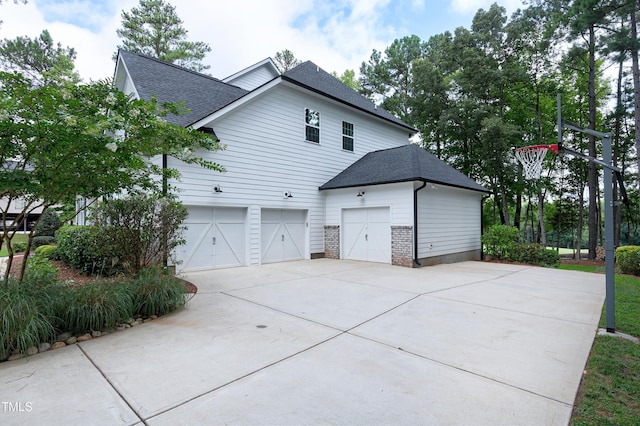 view of home's exterior with a garage, roof with shingles, and driveway