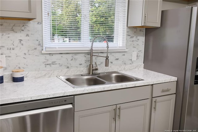 kitchen featuring a sink, light countertops, tasteful backsplash, and stainless steel appliances