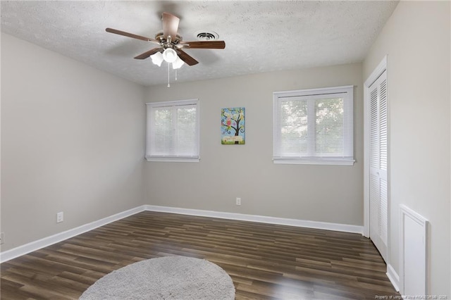 spare room featuring visible vents, wood finished floors, baseboards, a textured ceiling, and a ceiling fan
