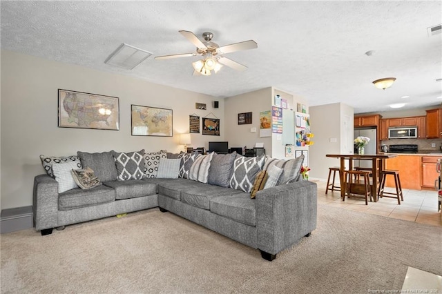living area with a ceiling fan, light colored carpet, a textured ceiling, and visible vents