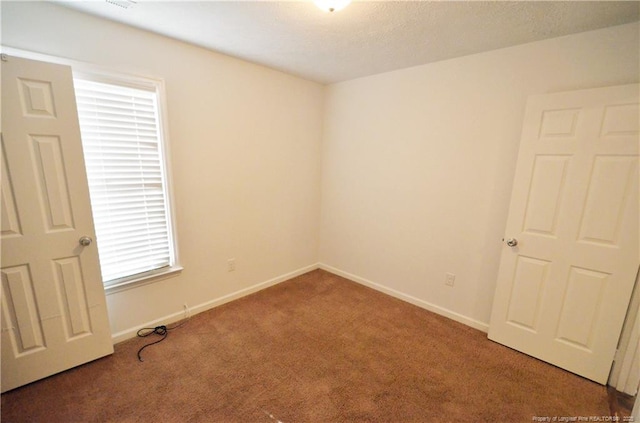 carpeted spare room featuring baseboards