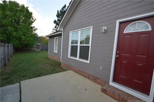 entrance to property featuring a patio, fence, and a yard