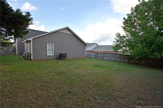 back of house with a lawn, central AC, and a fenced backyard