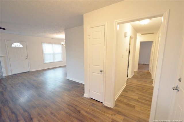 corridor featuring an inviting chandelier, baseboards, dark wood-style floors, and visible vents
