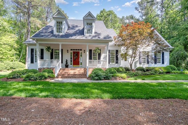 cape cod-style house featuring a shingled roof, a porch, and a front yard