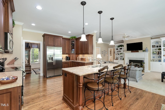 kitchen with a breakfast bar, a sink, stainless steel appliances, a ceiling fan, and open floor plan