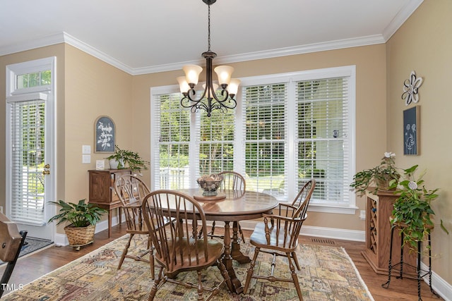 dining room with baseboards, ornamental molding, wood finished floors, and a chandelier