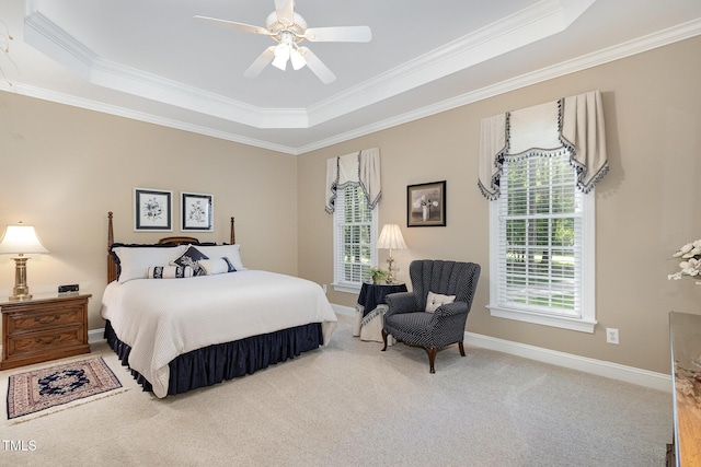 carpeted bedroom with a ceiling fan, a tray ceiling, ornamental molding, and baseboards