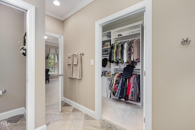 interior space featuring crown molding, baseboards, marble finish floor, and a walk in closet