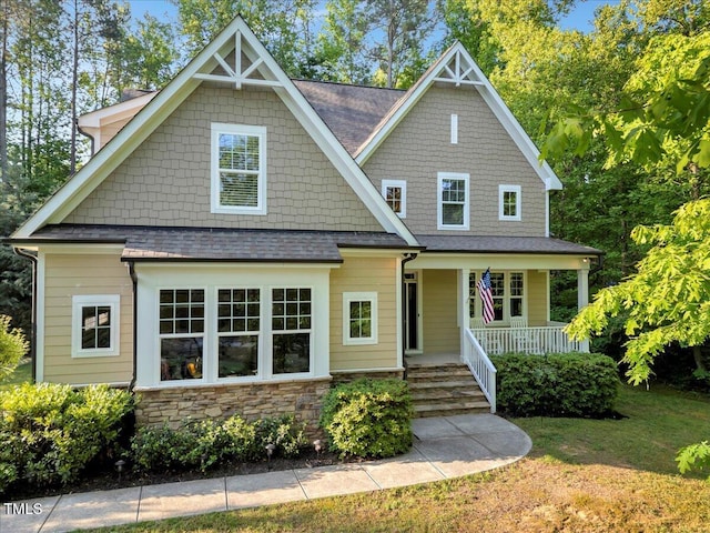 craftsman-style house featuring a porch, roof with shingles, and a front lawn
