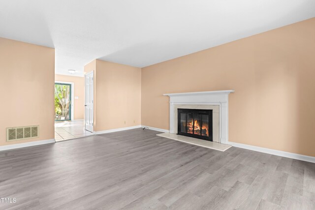 3029 Wycliff Rd, Raleigh, NC 27607 - unfurnished living room with visible vents, baseboards, a glass covered fireplace, and wood finished floors