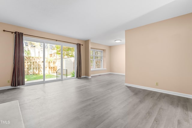 unfurnished living room featuring baseboards, wood finished floors, and visible vents