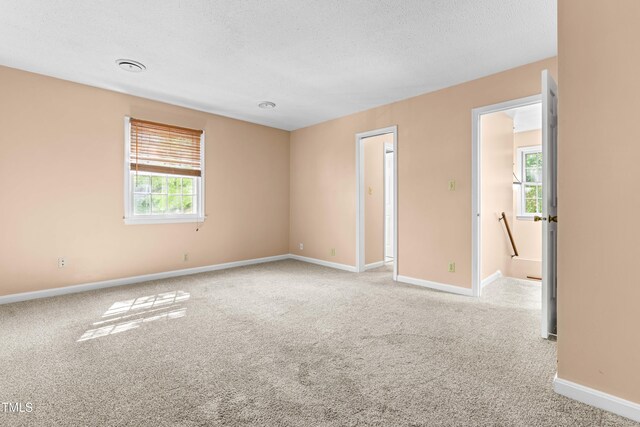 3029 Wycliff Rd, Raleigh, NC 27607 - carpeted empty room with baseboards, a textured ceiling, and a wealth of natural light