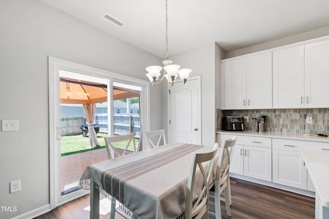 dining room featuring dark wood-type flooring, baseboards, visible vents, and an inviting chandelier