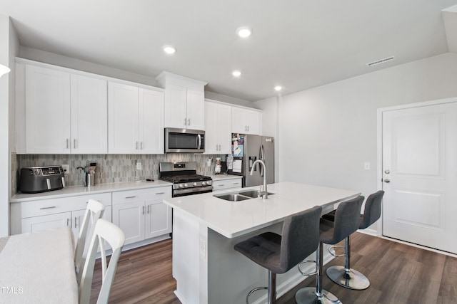 kitchen featuring visible vents, dark wood-style floors, tasteful backsplash, a sink, and stainless steel appliances