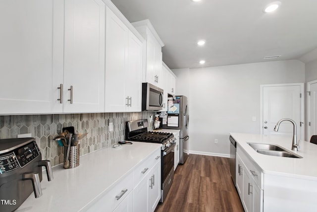 kitchen with backsplash, dark wood-style flooring, a sink, light countertops, and stainless steel appliances