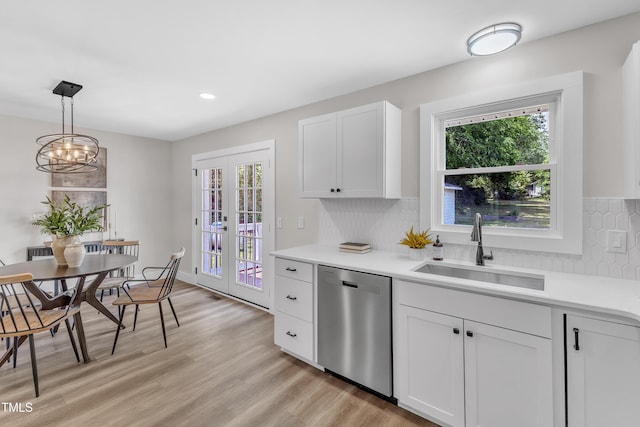 kitchen with a sink, stainless steel dishwasher, light wood-type flooring, and a healthy amount of sunlight