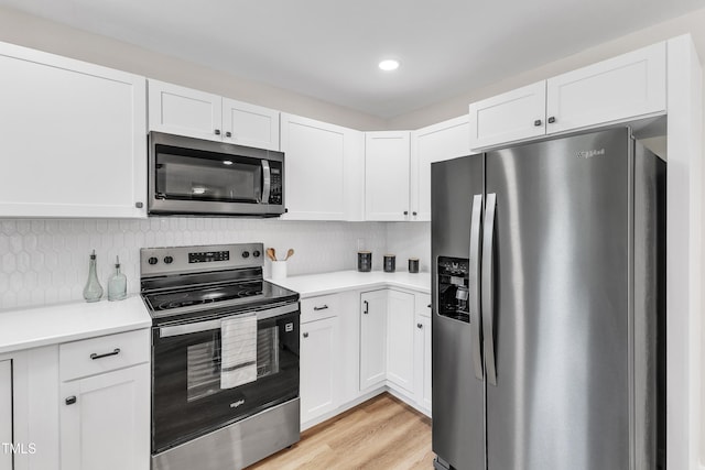 kitchen with light countertops, stainless steel appliances, white cabinetry, and backsplash