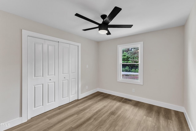 unfurnished bedroom featuring baseboards, ceiling fan, wood finished floors, and a closet