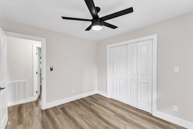 unfurnished bedroom with baseboards, visible vents, wood finished floors, and a closet