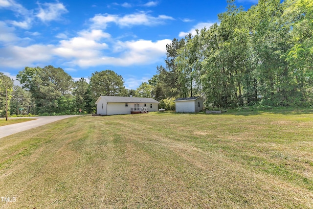 view of yard with a storage unit, an outdoor structure, and concrete driveway