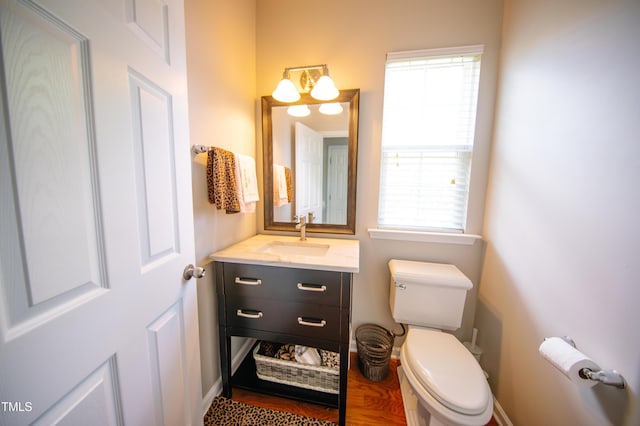 bathroom featuring toilet, baseboards, wood finished floors, and vanity