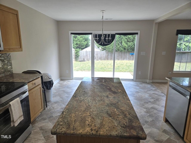 kitchen with dark stone countertops, a notable chandelier, stone finish floor, and stainless steel appliances