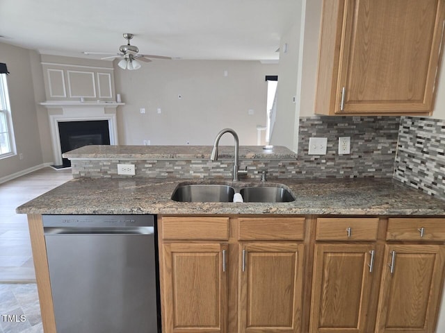 kitchen with ceiling fan, tasteful backsplash, a sink, dark stone countertops, and dishwasher
