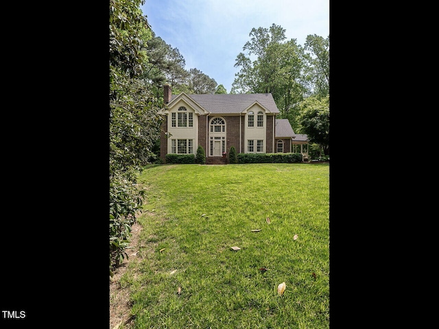 colonial inspired home with a chimney and a front yard