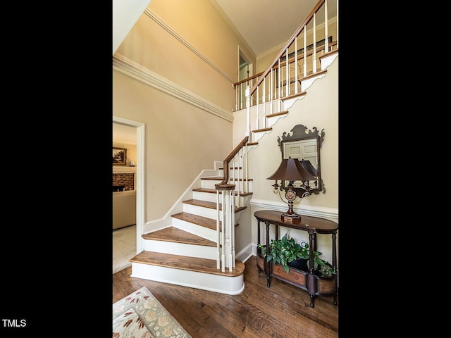 stairs with crown molding, baseboards, and wood finished floors