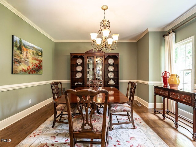 dining room with an inviting chandelier, baseboards, crown molding, and wood finished floors