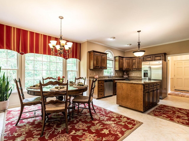 kitchen featuring a sink, a chandelier, a center island, stainless steel appliances, and decorative backsplash