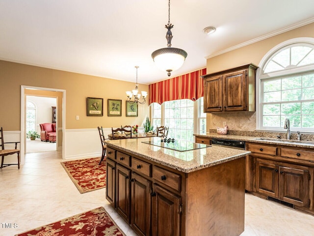 kitchen featuring an inviting chandelier, black electric stovetop, a sink, decorative light fixtures, and a kitchen island