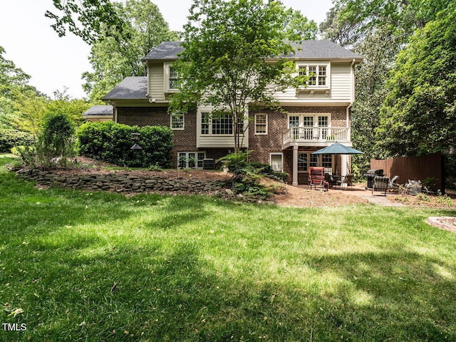 rear view of house featuring a yard, brick siding, fence, and a patio area