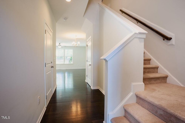 stairway featuring baseboards, wood finished floors, and a chandelier