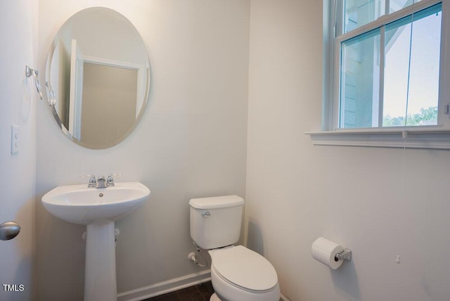 bathroom featuring plenty of natural light, a sink, baseboards, and toilet